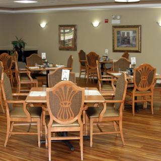 A spacious dining area featuring wooden tables and chairs, set in a warmly decorated interior.