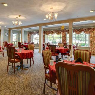 Elegant dining area with tables and chairs, featuring large windows and chandeliers.