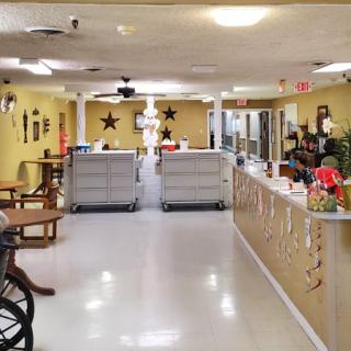 A welcoming indoor facility with yellow walls and a service counter, featuring tables and decorative elements.
