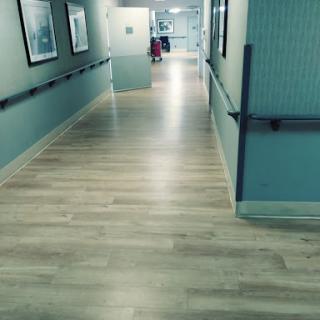 A view of a hospital hallway with light-colored flooring and walls.