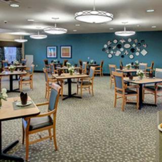 A well-decorated dining room with neatly arranged tables and chairs, featuring modern lighting fixtures.