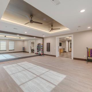 A modern fitness room with mirrors, yoga mats, and weights.