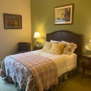 A cozy bedroom with a neatly made bed, flanked by two lamps on side tables.