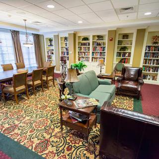 A cozy library reading room featuring bookshelves, comfortable seating, and a large table.