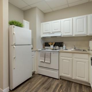 A small kitchen with white cabinetry, a refrigerator, and a stove.