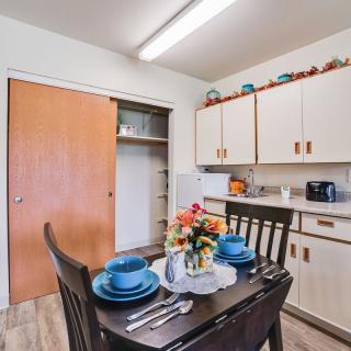 A cozy kitchen area with a set dining table and cabinets.