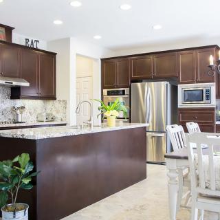 A modern kitchen featuring stainless steel appliances, wood cabinets, and a spacious dining area with a marble countertop.
