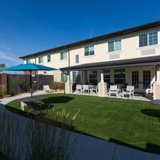 A modern two-story building with a well-maintained garden and outdoor seating area.