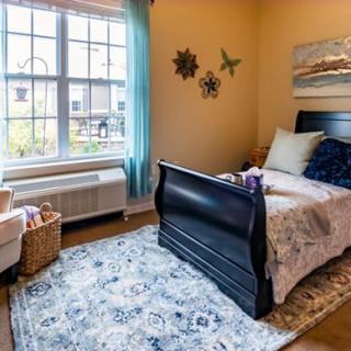 A cozy bedroom with a large window, single bed, and decorative elements.