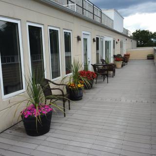 A spacious outdoor deck with seating and potted plants along the building exterior.