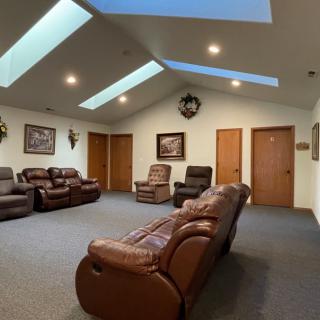 A spacious living room with multiple recliner sofas and ample natural light from skylights.
