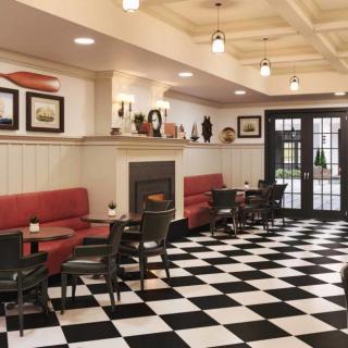 A vintage-style cafe interior featuring red seating, black chairs, a checkered floor, and cozy lighting.