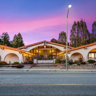 A well-lit restaurant building at sunset with a picturesque sky.