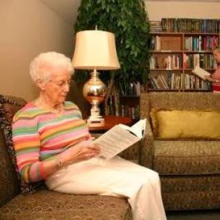 An elderly woman enjoying a quiet moment reading in her cozy living room.