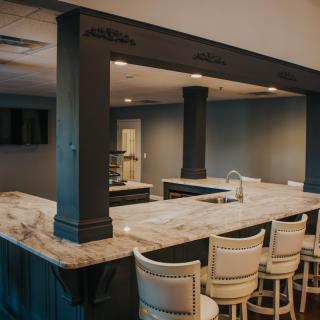 A stylish home bar with a marble countertop and cozy seating.