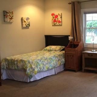A cozy bedroom with a single bed, nightstand, and decorative wall art.