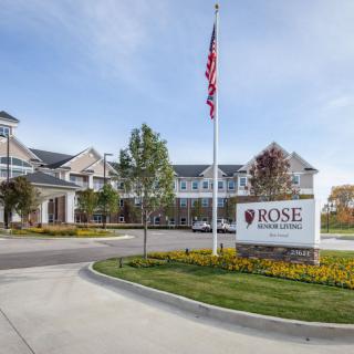 A view of a residential building with an American flag and landscaped driveway.