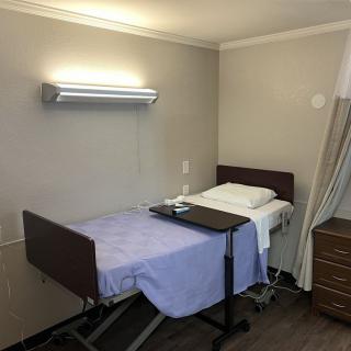 A simple hospital room with a bed and medical equipment.