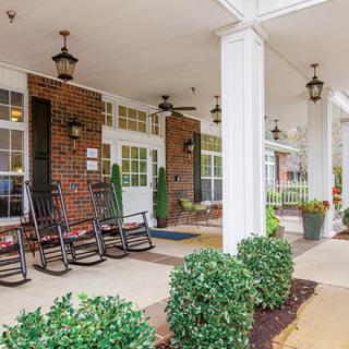 A cozy porch with rocking chairs, greenery, and decorative lanterns.