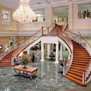 A luxurious hotel lobby featuring a grand staircase and elegant chandelier.
