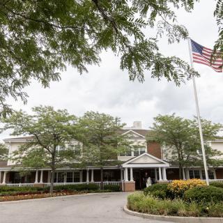 A view of a building surrounded by trees and an American flag flying on a cloudy day.