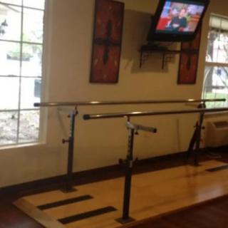 A dance studio with a ballet barre and a television mounted on the wall.