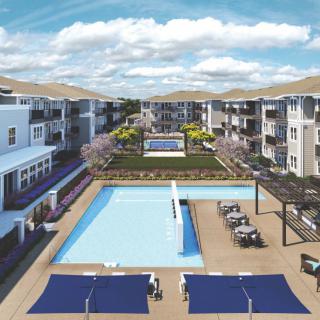 Aerial view of a modern apartment complex featuring a central swimming pool and landscaped outdoor spaces.