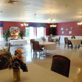 A spacious dining room with elegantly arranged tables and chairs, decorated with plants and wall art.