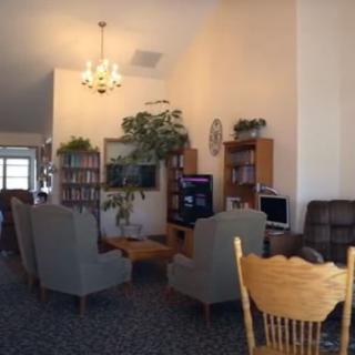 A cozy living room with chairs, a television, and bookshelves.