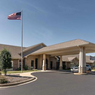 The entrance of a building with an American flag waving in the breeze under a clear blue sky.