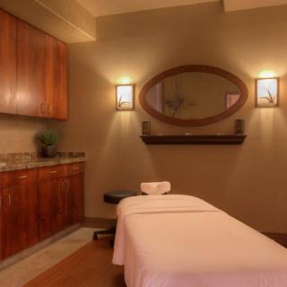 A serene massage room with ambient lighting and a comfortable bed.