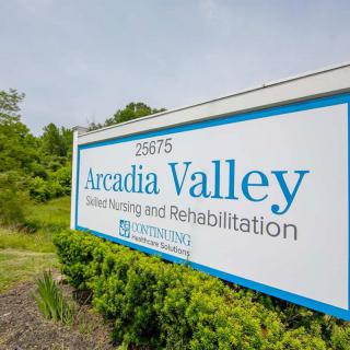 A sign for Arcadia Valley Skilled Nursing and Rehabilitation center, set amidst greenery.