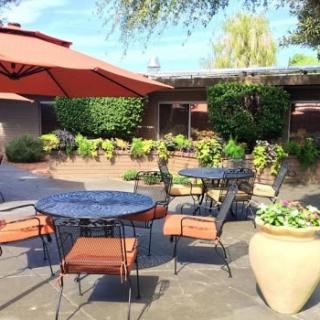A cozy outdoor patio with tables and chairs, perfect for enjoying a meal surrounded by lush greenery.