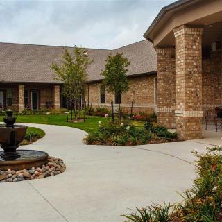 A beautifully landscaped courtyard with a brick building and fountain.