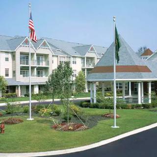 Exterior view of a residential building with well-maintained landscaping and flags.