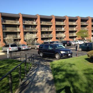 A sunny day showcasing an apartment building with parked cars in the foreground.