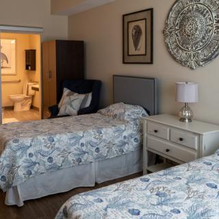 A cozy bedroom with two twin beds, decorative artwork on the walls, and a lamp on the bedside table.