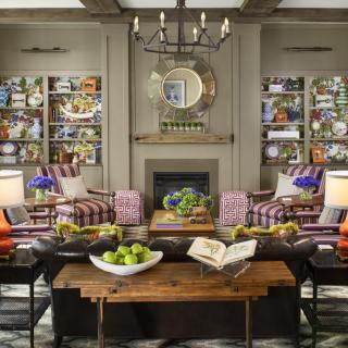 A cozy living room featuring a fireplace, bookshelves, and elegant furniture with vibrant decor.