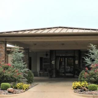 The entrance of a building surrounded by landscaped greenery and flowers.