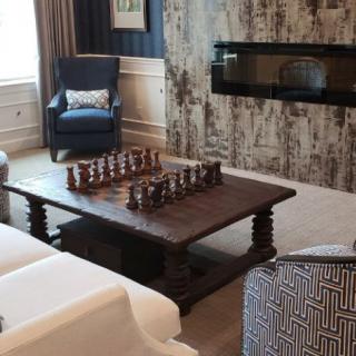 A cozy living room with a large chess set on a wooden coffee table, featuring modern decor and a fireplace.