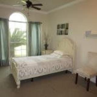 A cozy bedroom with a single bed, featuring large windows and minimalist decor.
