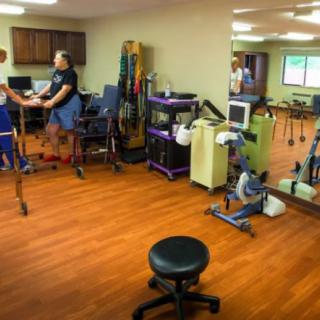 A physical therapy room with various exercise equipment and people engaging in rehabilitation exercises.