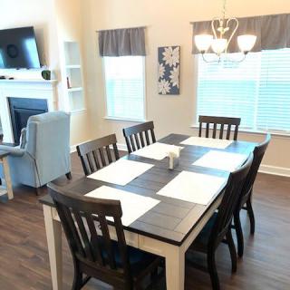 A modern dining area with a table set for six, adjacent to a cozy living space.