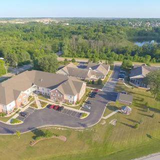 Aerial view of a suburban community with buildings surrounded by greenery and a parking lot.