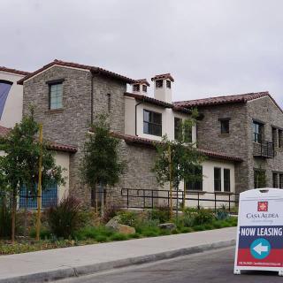 A modern residential building with a 'For Lease' sign in front.