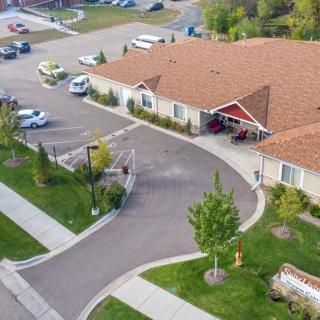 Aerial view of a suburban building with a parking lot and landscaped greenery.
