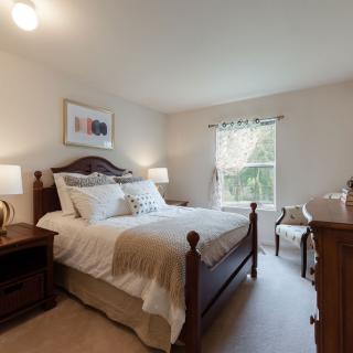 A cozy bedroom with a large bed, two nightstands, and a window letting in natural light.