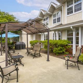 A sunny patio area with outdoor furniture and a gazebo in a residential setting.