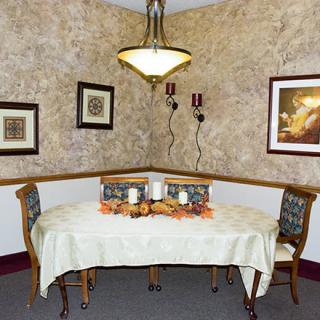 A cozy dining area with a decorative table setting, featuring wall art and a chandelier.
