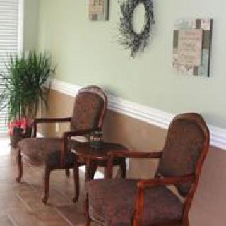 A cozy waiting area with two upholstered chairs, decorated walls, and a potted plant.